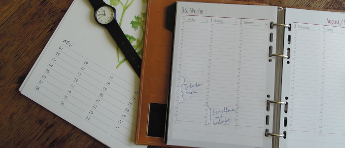 Kalender mit Terminen und Armbanduhr